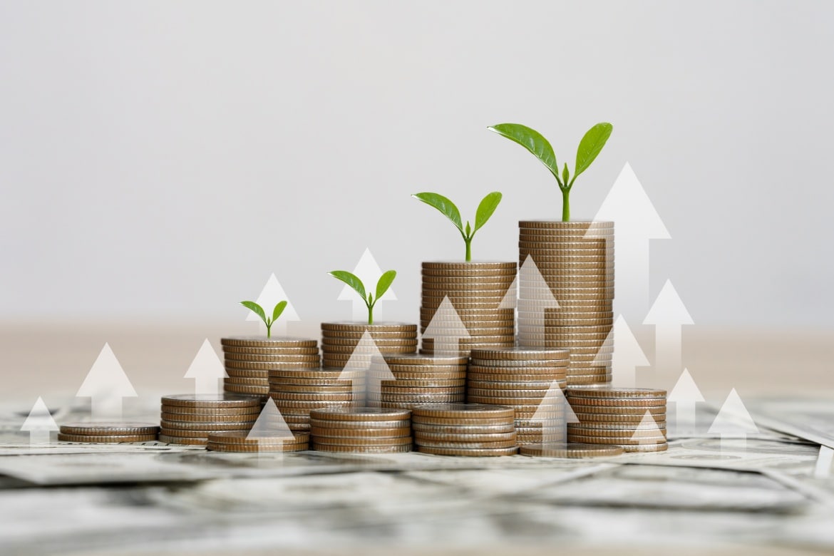 Several stacks of coins with arrows pointing upward indicating passive income and investing with money scaling.