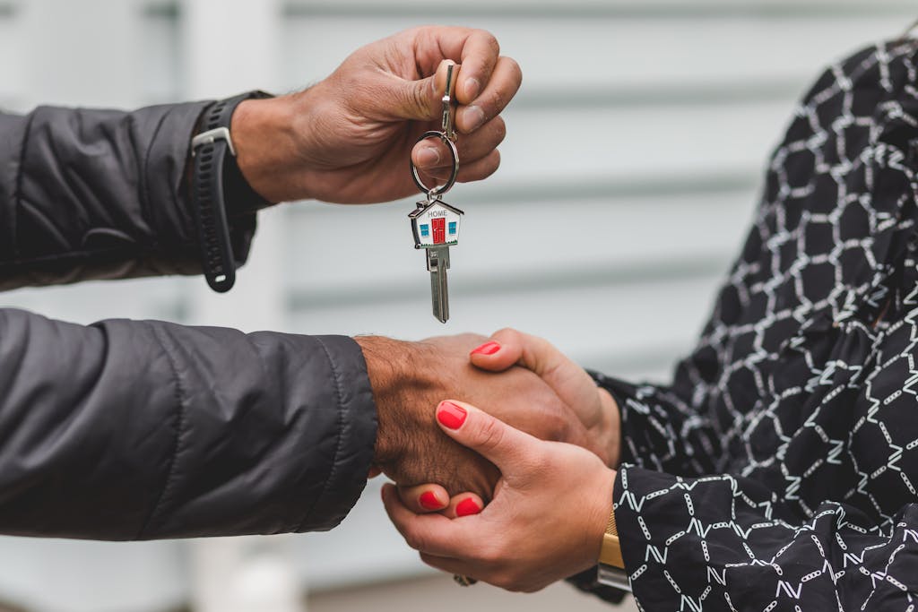 Entry level jobs finance with close-up of a realtor handing over a house key to a new homeowner, symbolizing ownership and investment.