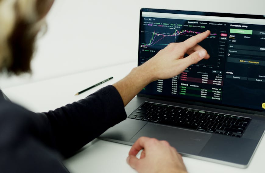 A person analyzing stock market graphs on a laptop screen, showcasing trading insights.