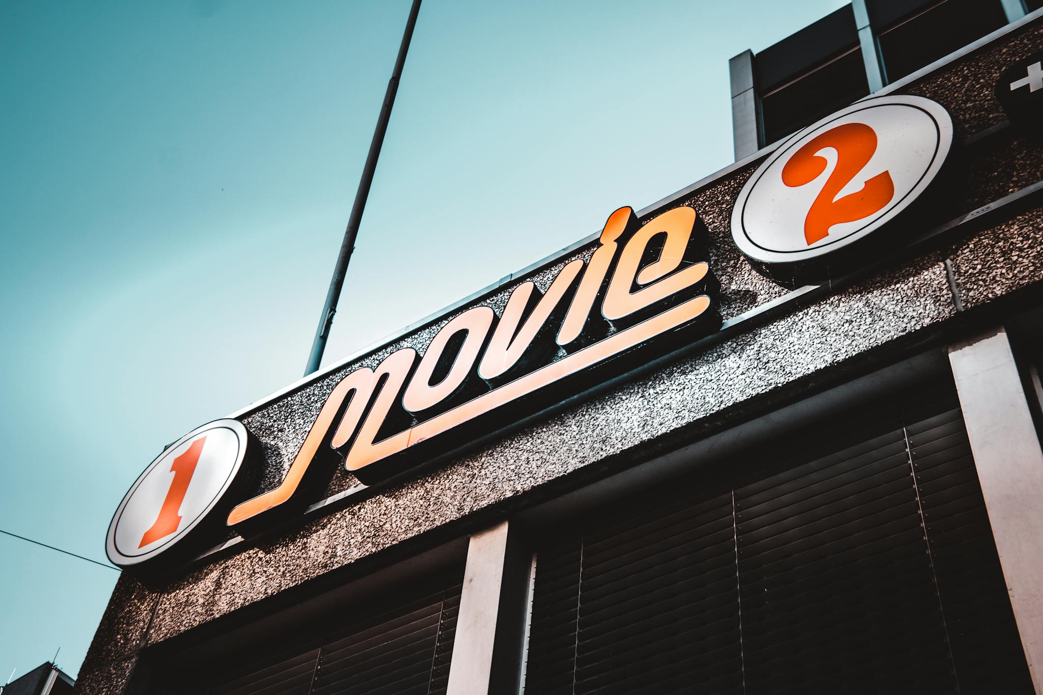 Low-angle shot of a vintage movie theater sign in bern, switzerland with a clear blue sky.