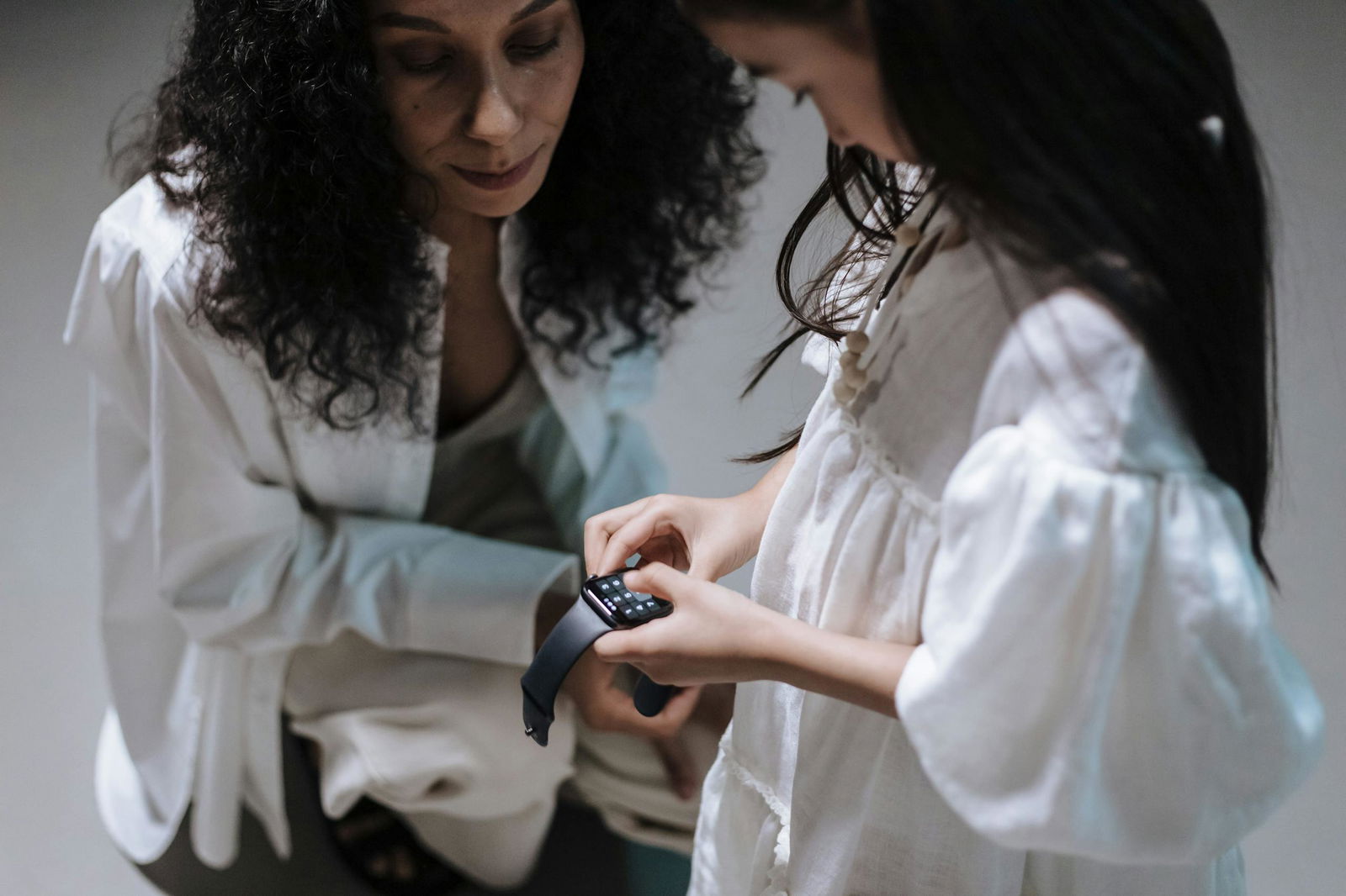 A mother and daughter interact with a smartwatch, swearable technology for children
