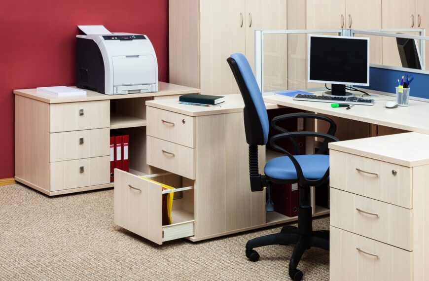 An organized office workspace featuring a desk, chair, several cabinets, a printer, and a desktop computer.