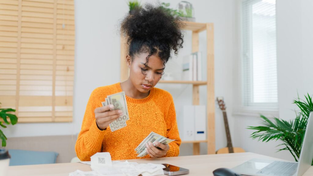 Close-up of a woman stacking bills to track progress in revenge saving.