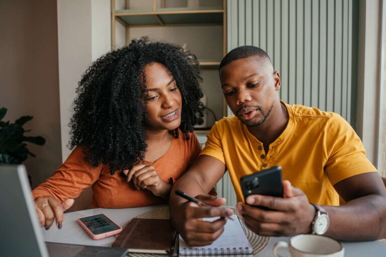 Couple reviewing monthly budget at home with a focus on revenge saving strategies.