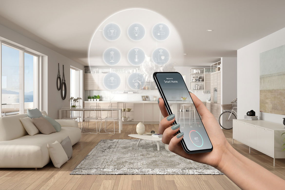 A hand holds a smartphone with an app titled "smart home" in front of a view of an open-concept living room.