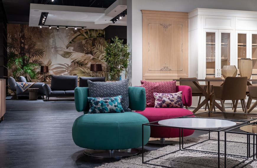 Contemporary trendy interior design of living room with multicolored soft chairs represented in furniture showroom