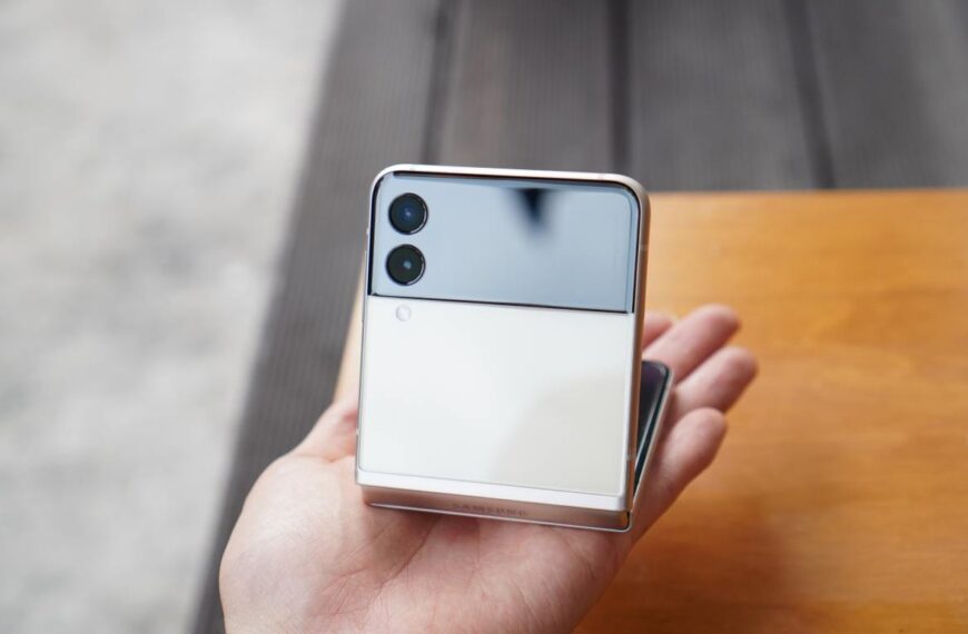 A person holding a half-folded smartphone with dual rear cameras and a reflective surface. The hinge is clearly visible.