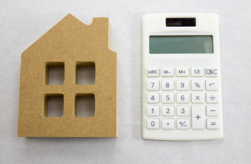 A cardboard cutout and a calculator sit side by side on a neutral surface