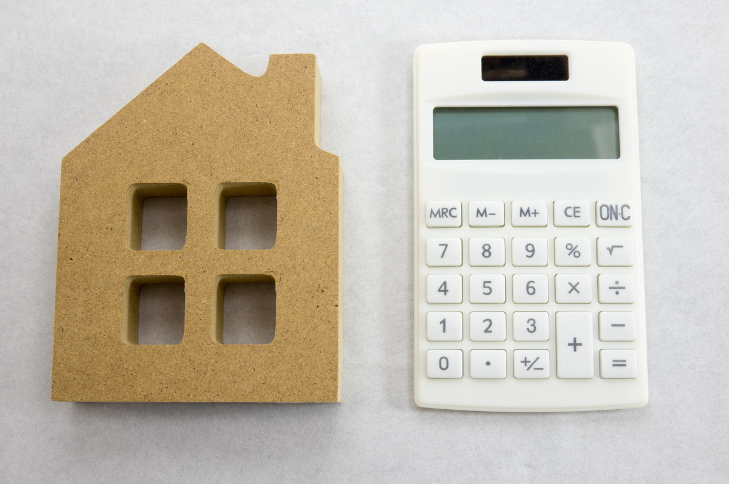 A cardboard cutout and a calculator sit side by side on a neutral surface