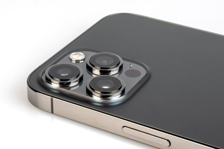 A close-up view shows an iphone with a silver edge and a black back that's lying screen side down.