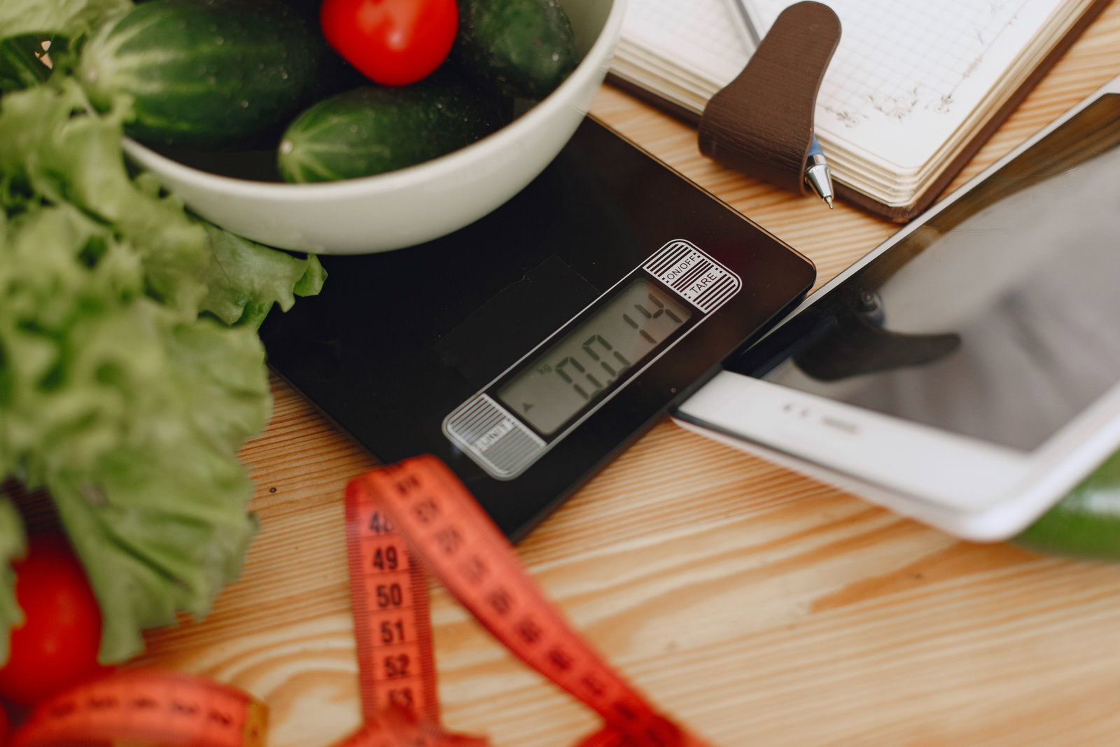 A bowl of fresh vegetables on a kitchen scale with measurement tools, depicting a healthy lifestyle.