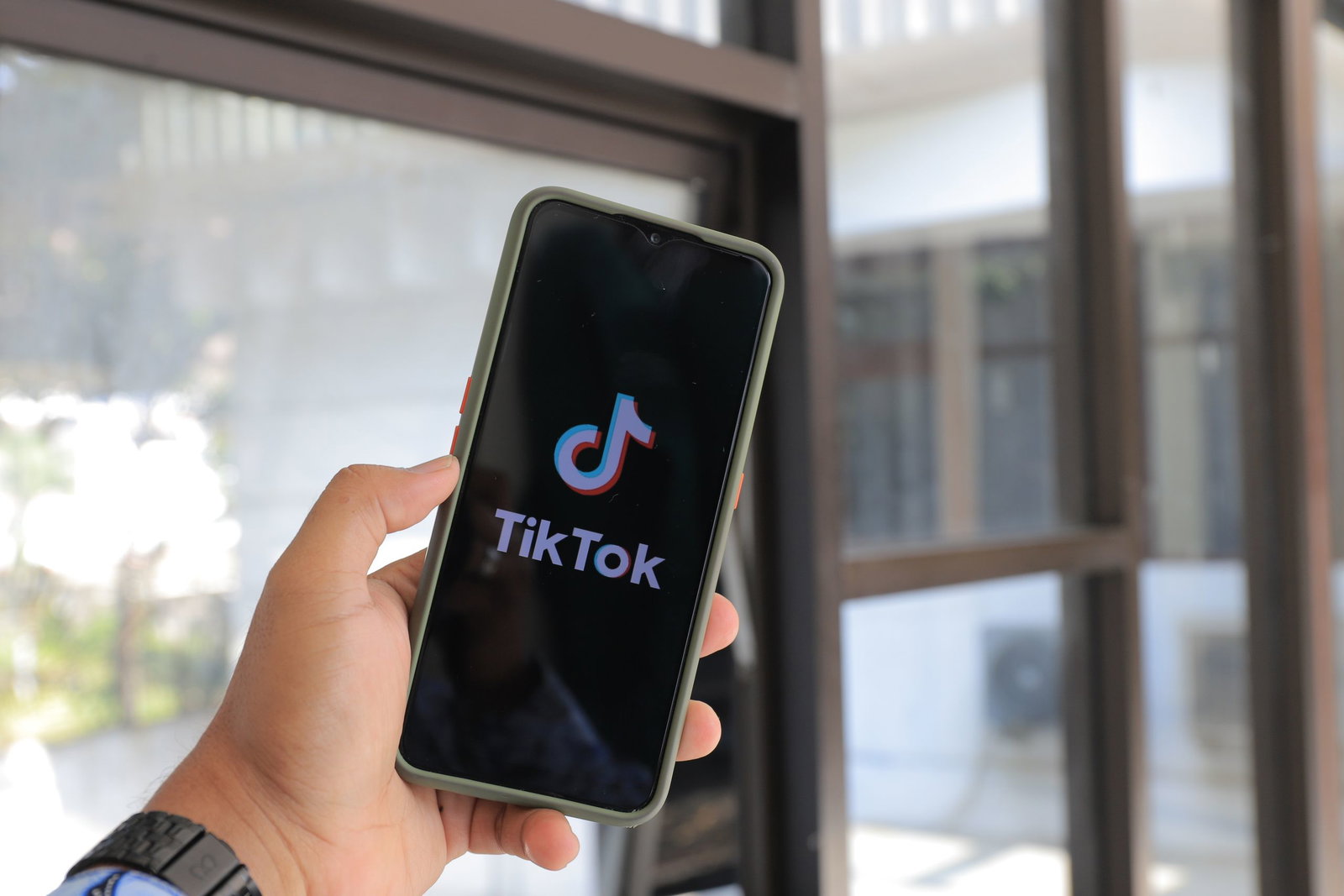 Close-up of a hand holding a smartphone displaying the tiktok app indoors.