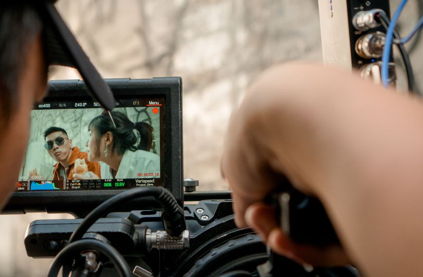 Close-up of a video camera display filming an outdoor scene with a crew.