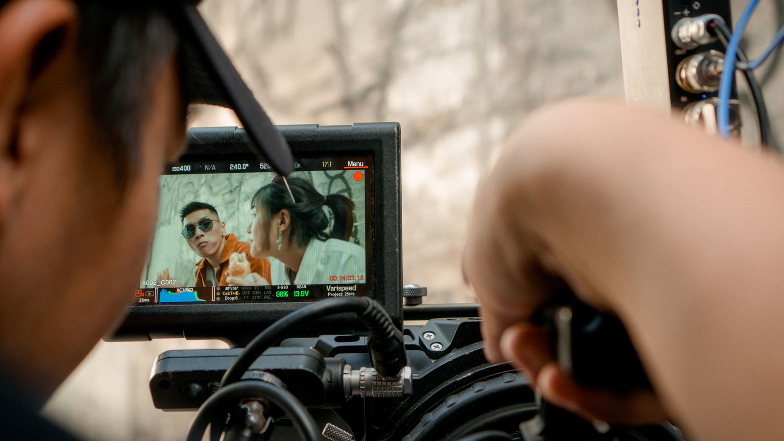 Close-up of a video camera display filming an outdoor scene with a crew.